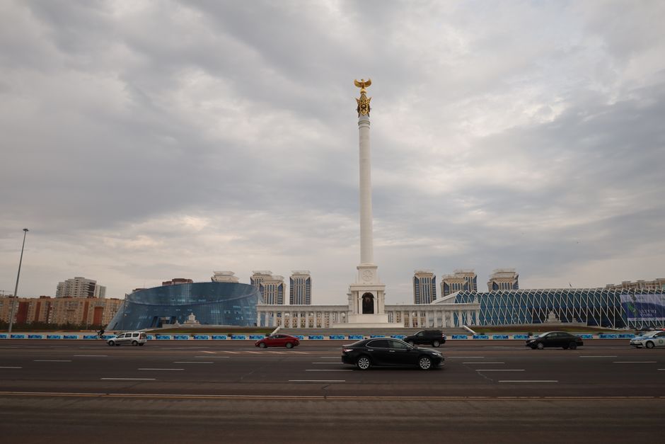 Astana's iconic Independence Square monument against a dramatic cloudy sky.