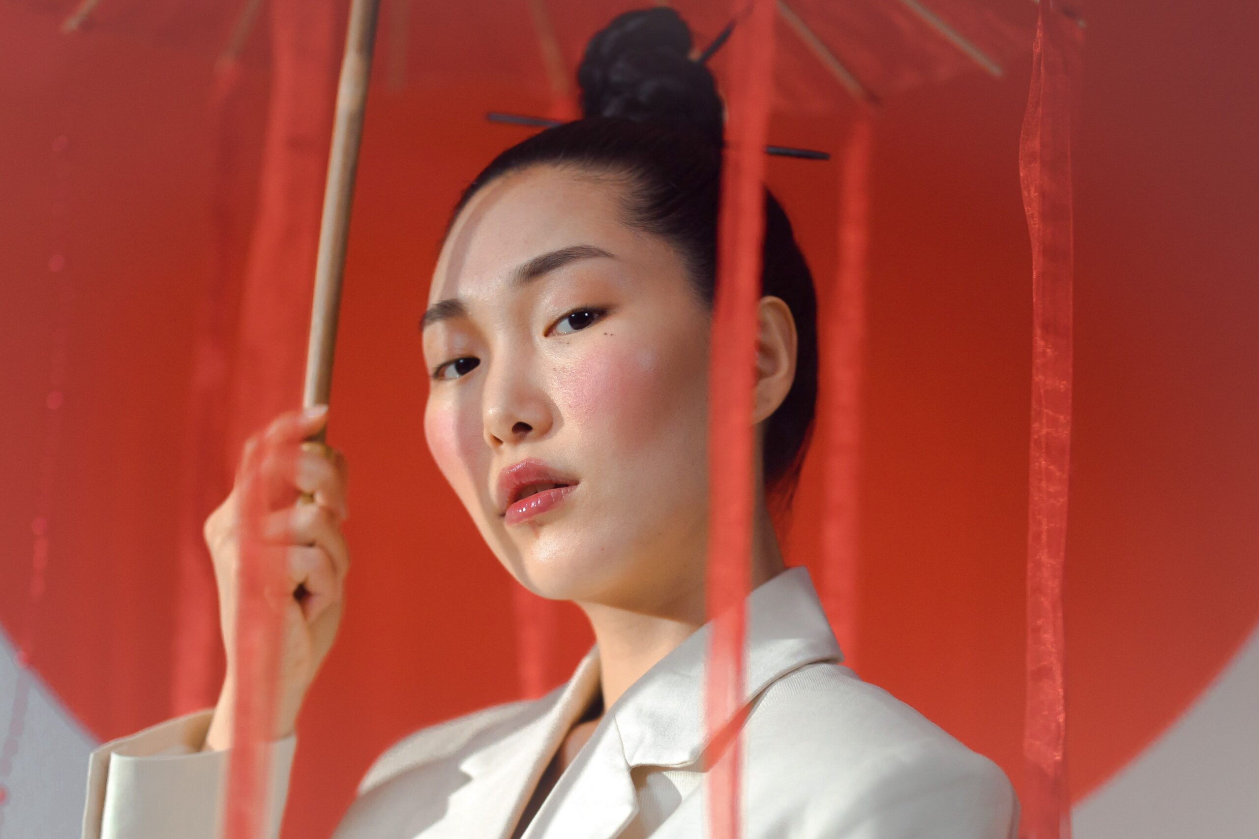 Portrait of an elegant woman with a red parasol and hair bun. Classic and sophisticated look.